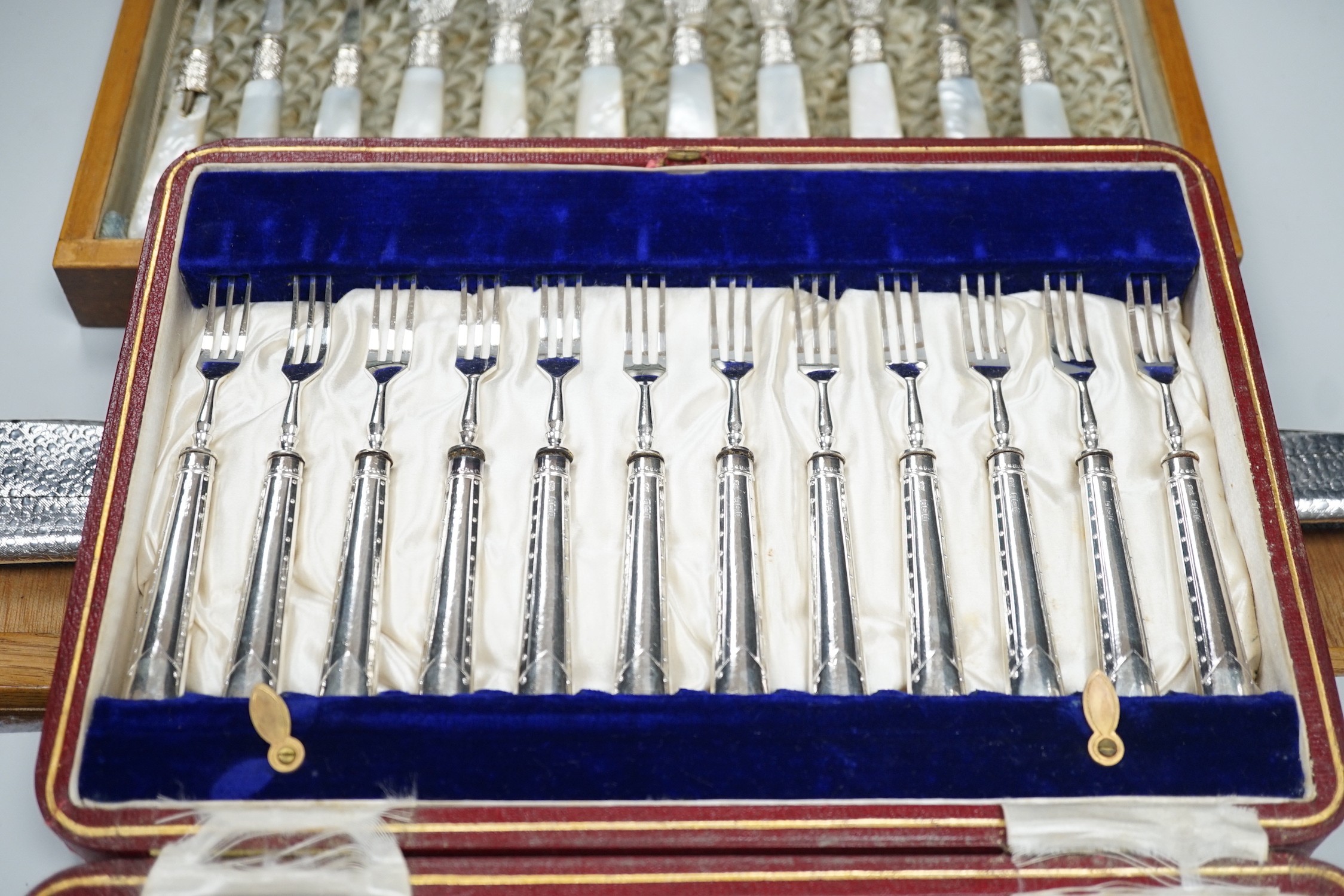 A cased set of twelve pairs of Victorian mother of pearl handed silver fish eaters (fork missing) R.F. Mosley & Co, Sheffield, 1894/1895 and a later cased set of twelve pairs of silver handled dessert eaters.